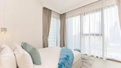 a bedroom with a white bed and large windows at Burj Khalifa view with Grass Turf Balcony-Downtown by Tanami Holiday Homes in Dubai