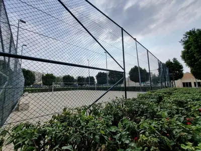 a tennis court behind a chain link fence at YALLA REMRAAM in Dubai