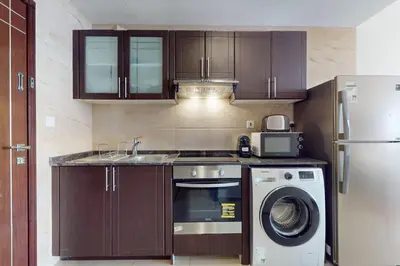 a kitchen with wooden cabinets and a washer and dryer at Siraj Tower - Colourful Studio in Dubai