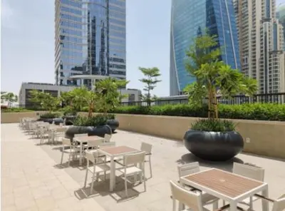 a patio with tables and chairs in a city at Modern Brand New 1 BR Apartment in ZADA Tower in Dubai