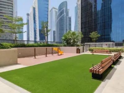 a park with benches and green grass in a city at Modern Brand New 1 BR Apartment in ZADA Tower in Dubai