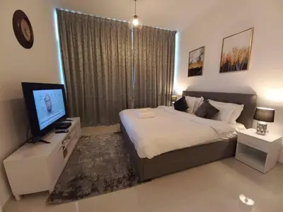 a bedroom with a bed and a television in it at Furnished Studio in Damac Hills in Dubai
