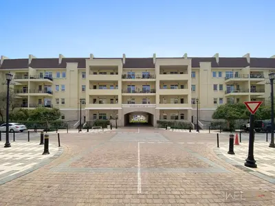 a large building with a parking lot in front of it at WelHome - Stylish Studio with Park Views in Regent House 2 in Dubai