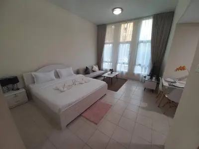 a bedroom with a large white bed and a desk at Cozy Studio in Discovery Gardens in Dubai