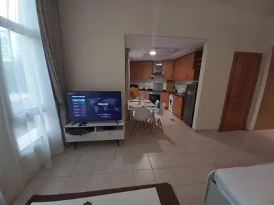 a living room with a television and a kitchen at Cozy Studio in Discovery Gardens in Dubai