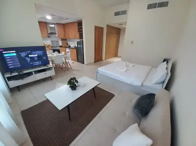 a living room with a couch and a tv at Cozy Studio in Discovery Gardens in Dubai