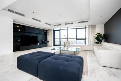 a large living room with a large blue ottoman at Luxe 6BR Penthouse with Burj View & Private Cinema in Dubai