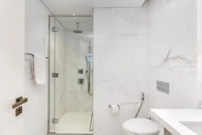 a white bathroom with a shower and a toilet at Luxe 6BR Penthouse with Burj View & Private Cinema in Dubai