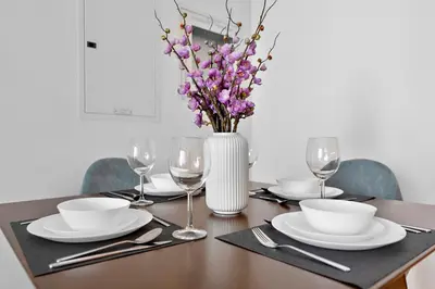 a table with a vase of flowers and plates and glasses at Stylish 1 BR in Dubai Marina in Dubai