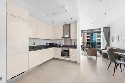 a kitchen with white cabinets and a living room at Stylish 1 BR in Dubai Marina in Dubai