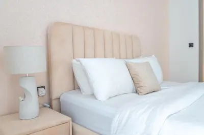 a white bed with white pillows and a lamp at Luxe 1BR 15mins-Beach Best Infinity Pool -Jumeirah Village Circle, JVC ,Dubai in Dubai