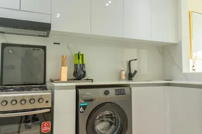 a kitchen with a washing machine and a stove at Luxe 1BR 15mins-Beach Best Infinity Pool -Jumeirah Village Circle, JVC ,Dubai in Dubai