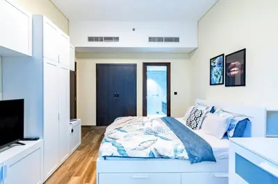 a white bedroom with a bed and a television at Jone brand-new aptm near Dubai Mall & Burj Khalifa in Dubai