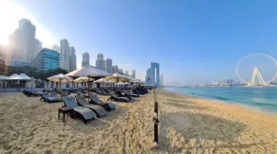 a beach with chairs and umbrellas and a city at Jumeirah Beach Residence - Rimal 3, Dubai Marina in Dubai