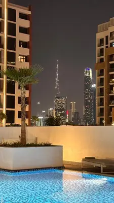 a swimming pool with a palm tree on a city skyline at Luxury Studio with big balcony Azizi Riviera Meydan in Dubai