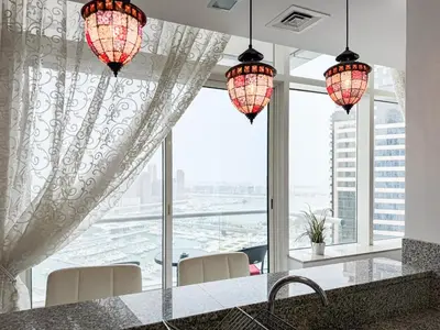 a kitchen with two chandeliers and a large window at SettlerHomes- Breathtaking 2BR Marina High-Floor in Dubai