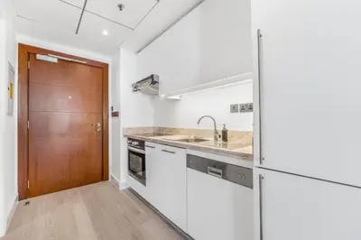a kitchen with white walls and a wooden door at Luxueux Studio, Top emplacement in Dubai