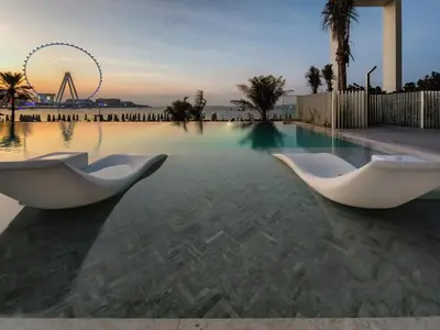 a swimming pool with two white chairs in the water at Stylish sea view from new 2BD La Vie in Dubai