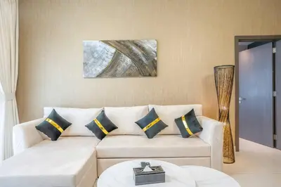 a living room with a white couch with blue pillows at Specious pool view One Bed room in Dubai