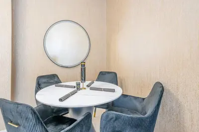 a table with chairs and a mirror on a wall at Specious pool view One Bed room in Dubai