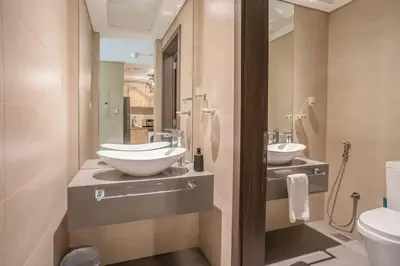 a bathroom with two sinks and a toilet at Specious pool view One Bed room in Dubai