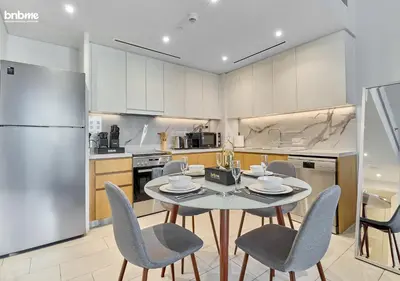 a kitchen with a table and chairs and a refrigerator at bnbme - Luxury 1BR La Vie Apt Beach Access Pool Gym Balcony & Stunning Dubai Eye Views in Dubai