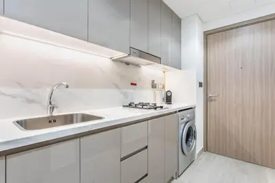 a white kitchen with a sink and a washing machine at Artist Heaven Studio! Riviera 35! 10 min Downtown in Dubai