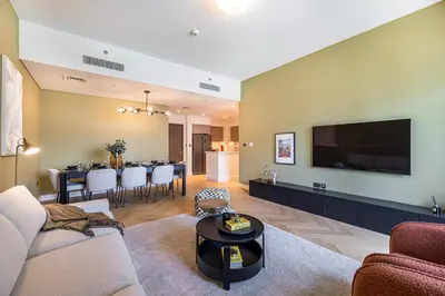a living room with a television and a dining room at Daniels Luxe 3BR Downtown with Skyline View in Dubai