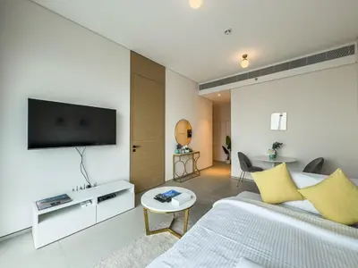 a living room with a bed and a tv on a wall at SettlerHomes - Chic Jumeirah Gate with Beach Access in Dubai