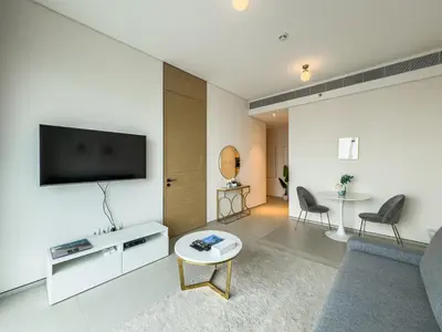 a living room with a couch and a tv on a wall at SettlerHomes - Chic Jumeirah Gate with Beach Access in Dubai