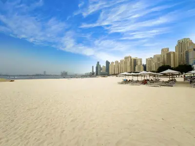 a beach with umbrellas and chairs and buildings at SettlerHomes - Chic Jumeirah Gate with Beach Access in Dubai