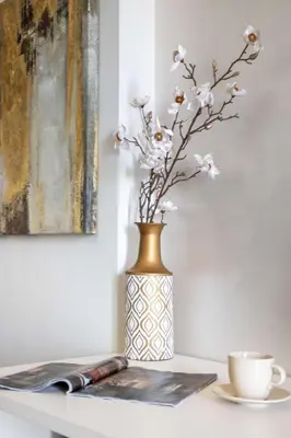 a vase with flowers in it on a table with a coffee cup at Frank Porter - Jwelz By Danube in Dubai