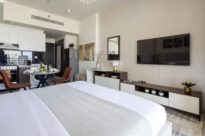 a bedroom with a large white bed and a kitchen at Frank Porter - Jwelz By Danube in Dubai