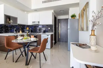 a kitchen with white cabinets and a table and chairs at Frank Porter - Jwelz By Danube in Dubai