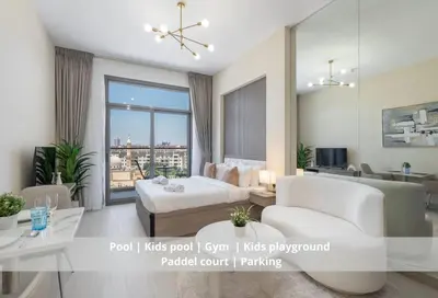 a living room with white furniture and a large window at Brand New Building * Czechin * Studio City in Dubai