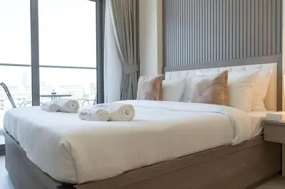 a large white bed with towels on top of it at Brand New Building * Czechin * Studio City in Dubai