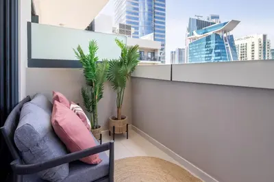 a living room with a couch and palm trees on a balcony at Frank Porter - Zada Tower in Dubai