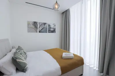 a bedroom with a bed and a window with curtains at Stylish 2 bedroom apartment in Sobha Hartland in Dubai