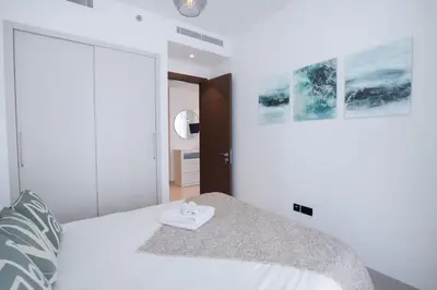 a white bedroom with a bed with a towel on it at Stylish 2 bedroom apartment in Sobha Hartland in Dubai
