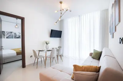 a living room with a couch and a table at Stylish 2 bedroom apartment in Sobha Hartland in Dubai