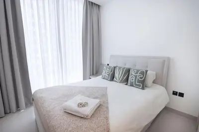 a white bedroom with a bed with a towel on it at Stylish 2 bedroom apartment in Sobha Hartland in Dubai