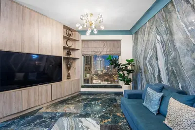 a living room with a large tv and a blue couch at FIRST CLASS 2BR Stunning Fountain View in Dubai