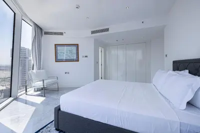 a white bedroom with a large bed and a chair at Panoramic LUX Apartment with Burj Khalifa View in Dubai