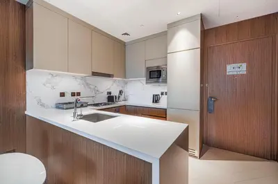 a kitchen with a white sink and a wooden door at Luxury 1BR The Address Opera, Downtown Dubai in Dubai