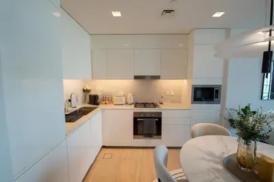 a kitchen with white cabinets and a table with chairs at The Palace 405 I Luxury 2BD I Dubai Creek Harbour in Dubai