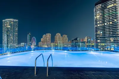 a large swimming pool with a city skyline at night at Livbnb - Sea and Marina View, Steps to Marina Walk in Dubai