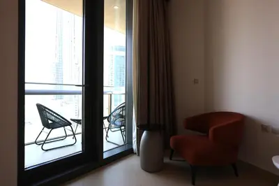 a room with a chair and a window with a balcony at Elegant 1BR Oasis Burj Vista Steps to Burj Khalifa - 11AB08 in Dubai