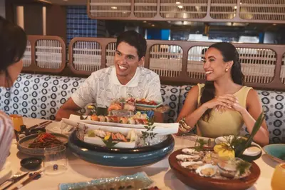 a man and woman sitting at a table with food at Four Seasons Resort Dubai at Jumeirah Beach in Dubai