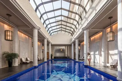 a woman stands in front of a swimming pool in a building at Four Seasons Resort Dubai at Jumeirah Beach in Dubai