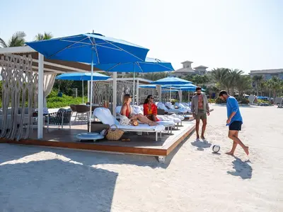 a group of people sitting on the beach under umbrellas at Four Seasons Resort Dubai at Jumeirah Beach in Dubai